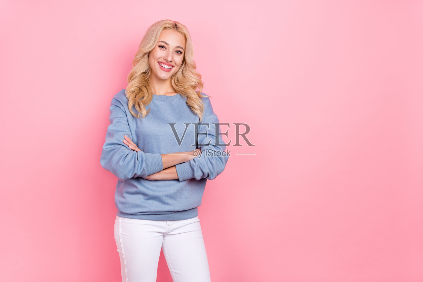 年轻漂亮女孩双手交叉，穿着休闲服装，经理形象，背景为粉色。照片摄影图片