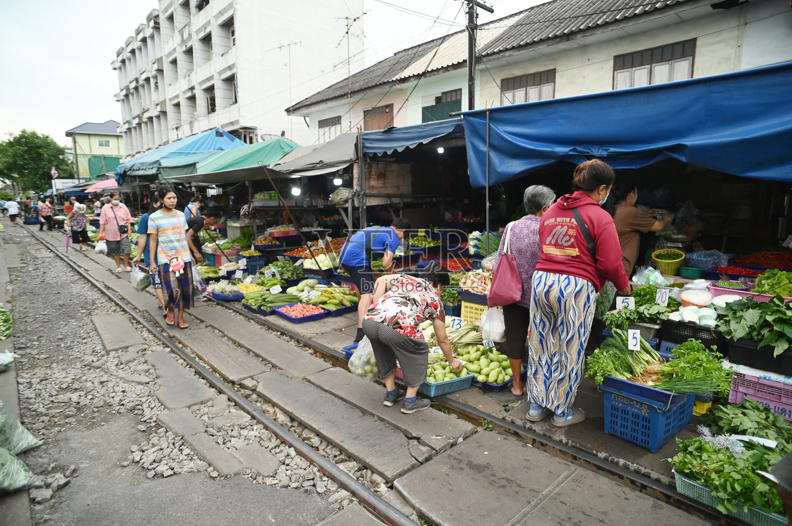 在马哈查伊车站，摊贩沿铁路出售蔬菜、水果和鲜花。当火车到来时，她会保持货架不动，因为它们较低。照片摄影图片
