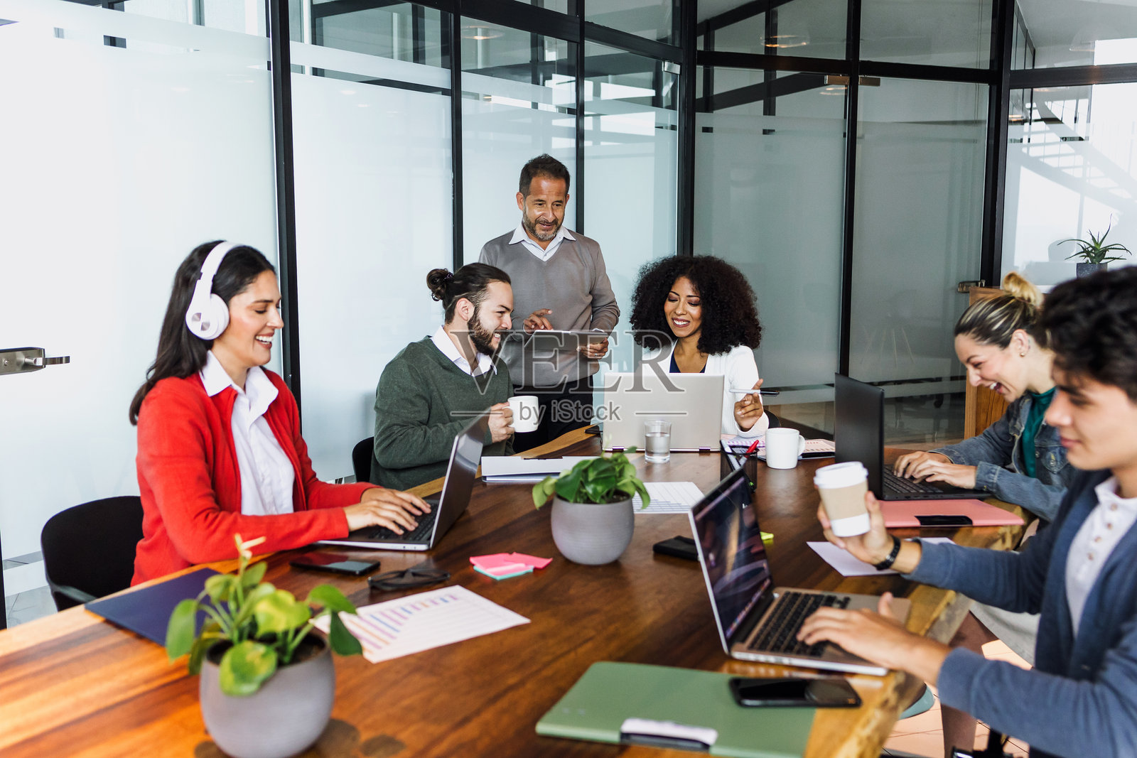 拉丁美洲的商务人士在墨西哥的办公室里讨论和工作，西班牙裔同事们使用笔记本电脑或电脑。照片摄影图片