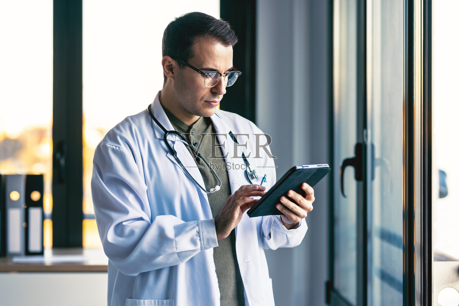 快乐的男性医生在医疗咨询中使用数字平板电脑工作。照片摄影图片