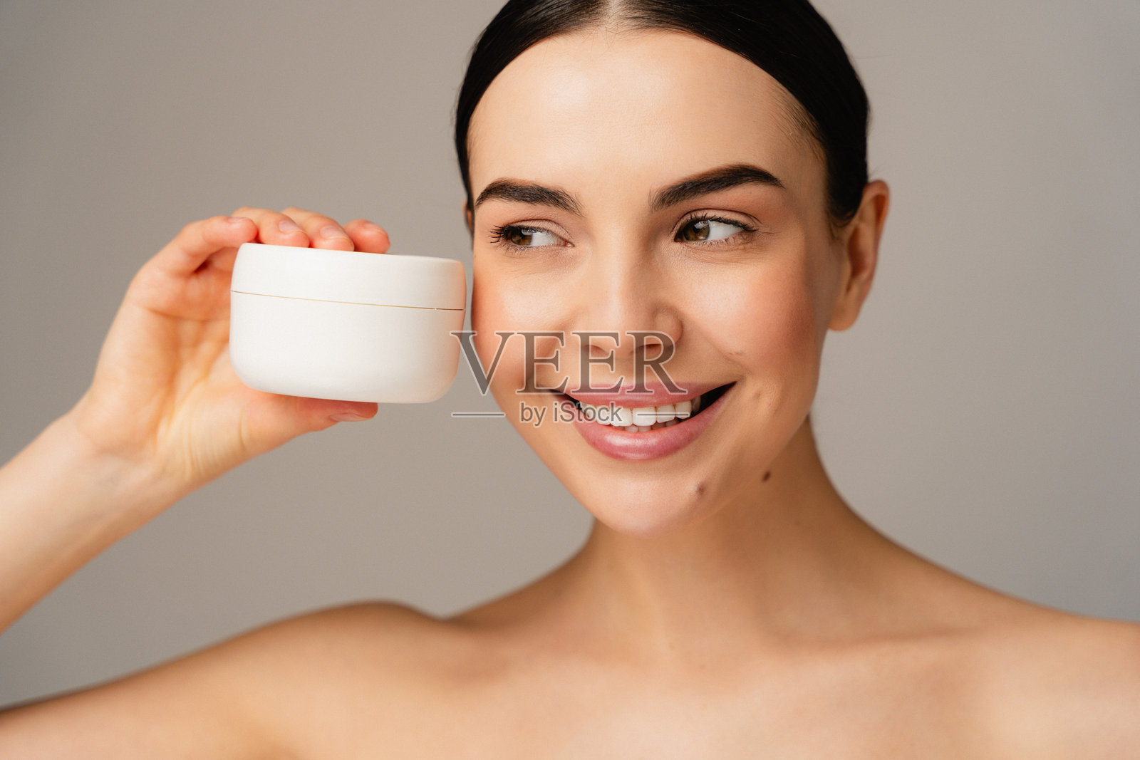 微笑的人在简约环境中拿着面霜容器照片摄影图片