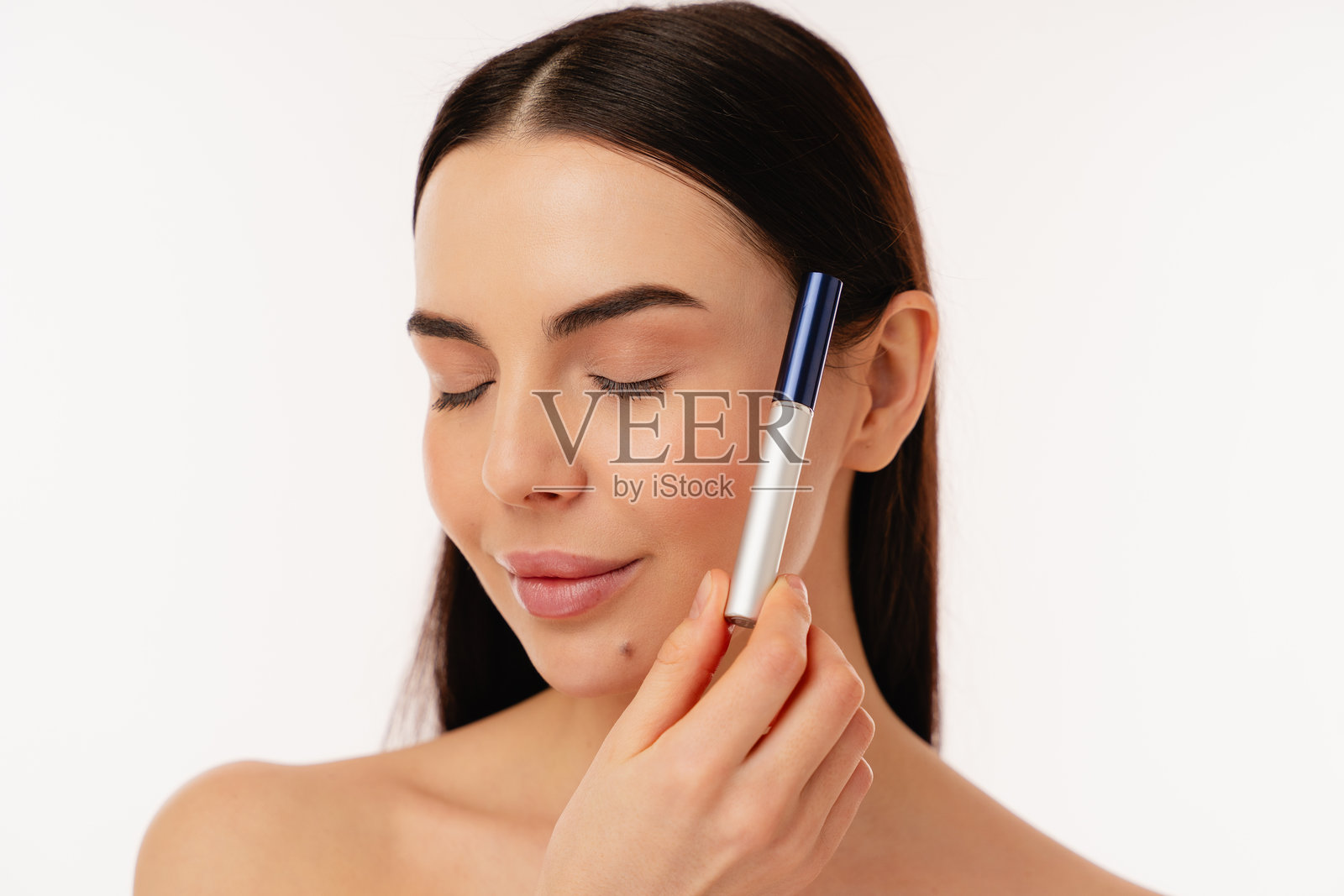 闭眼的女性在白色背景下手持美容产品照片摄影图片