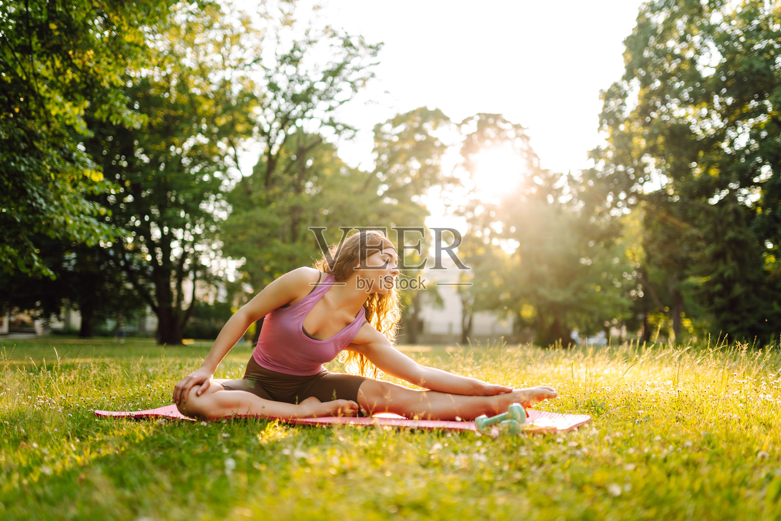 年轻女性穿着运动服在户外瑜伽垫上锻炼。照片摄影图片