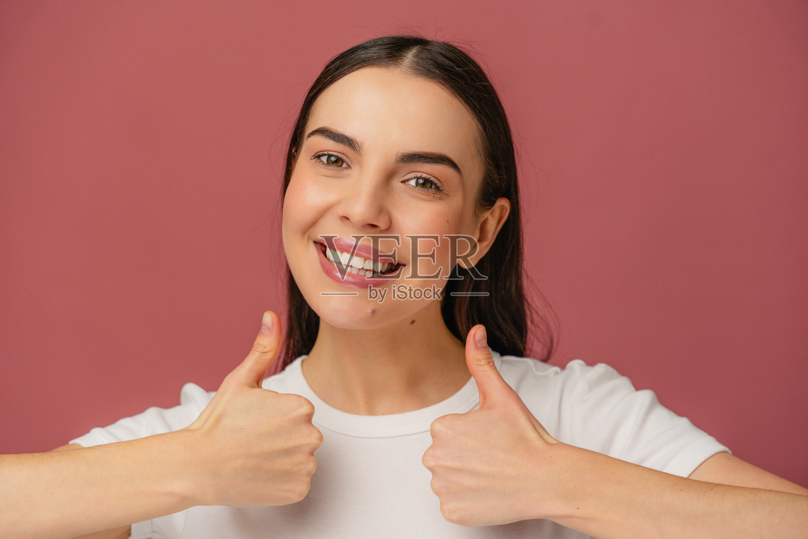 女性微笑着在彩色背景前做出两个大拇指向上的手势照片摄影图片