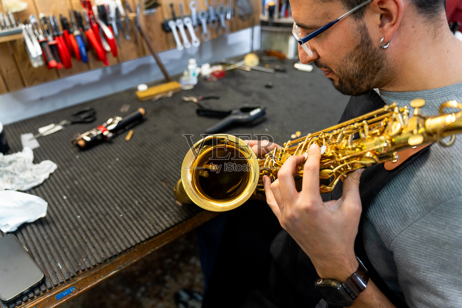 技术员在乐器工作室修理萨克斯ophone照片摄影图片