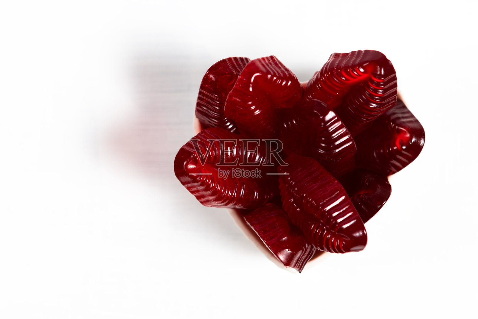 白色背景上的心形碗里装着红色橡皮糖嘴唇照片摄影图片