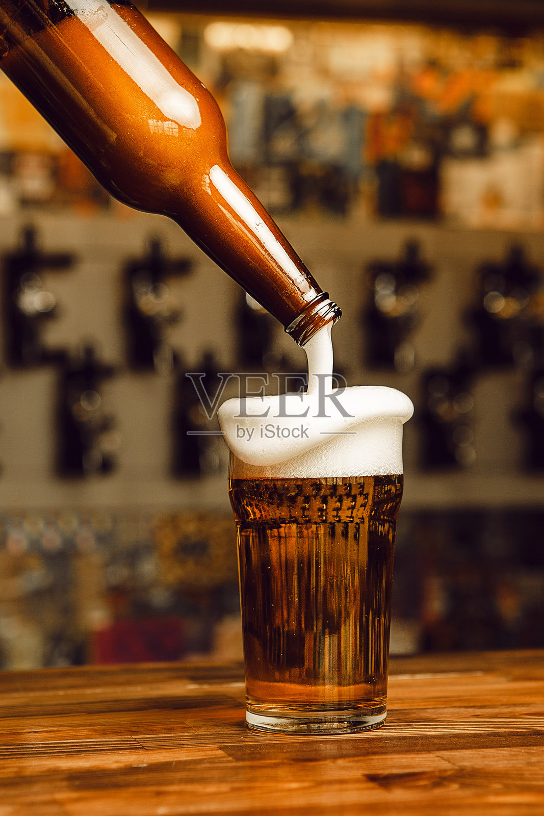在热闹的酒吧里将冰镇啤酒倒入冷却的酒杯中照片摄影图片