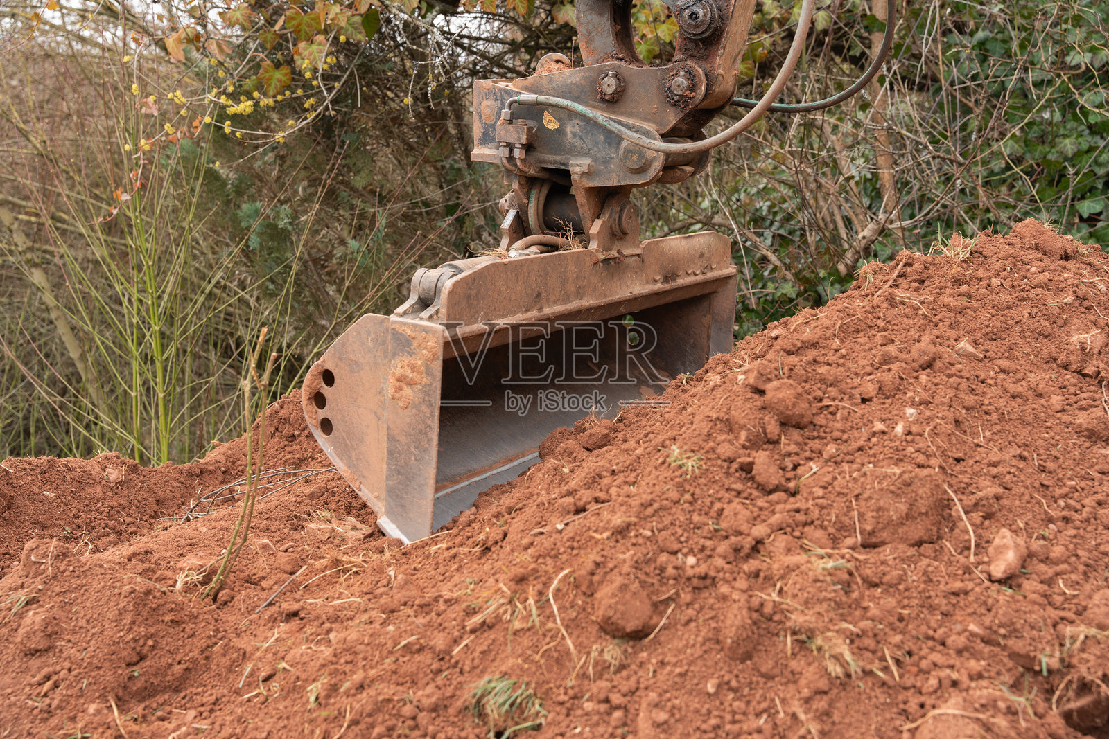 挖掘机铲斗特写，正在铲起含有石头的粘土土壤照片摄影图片