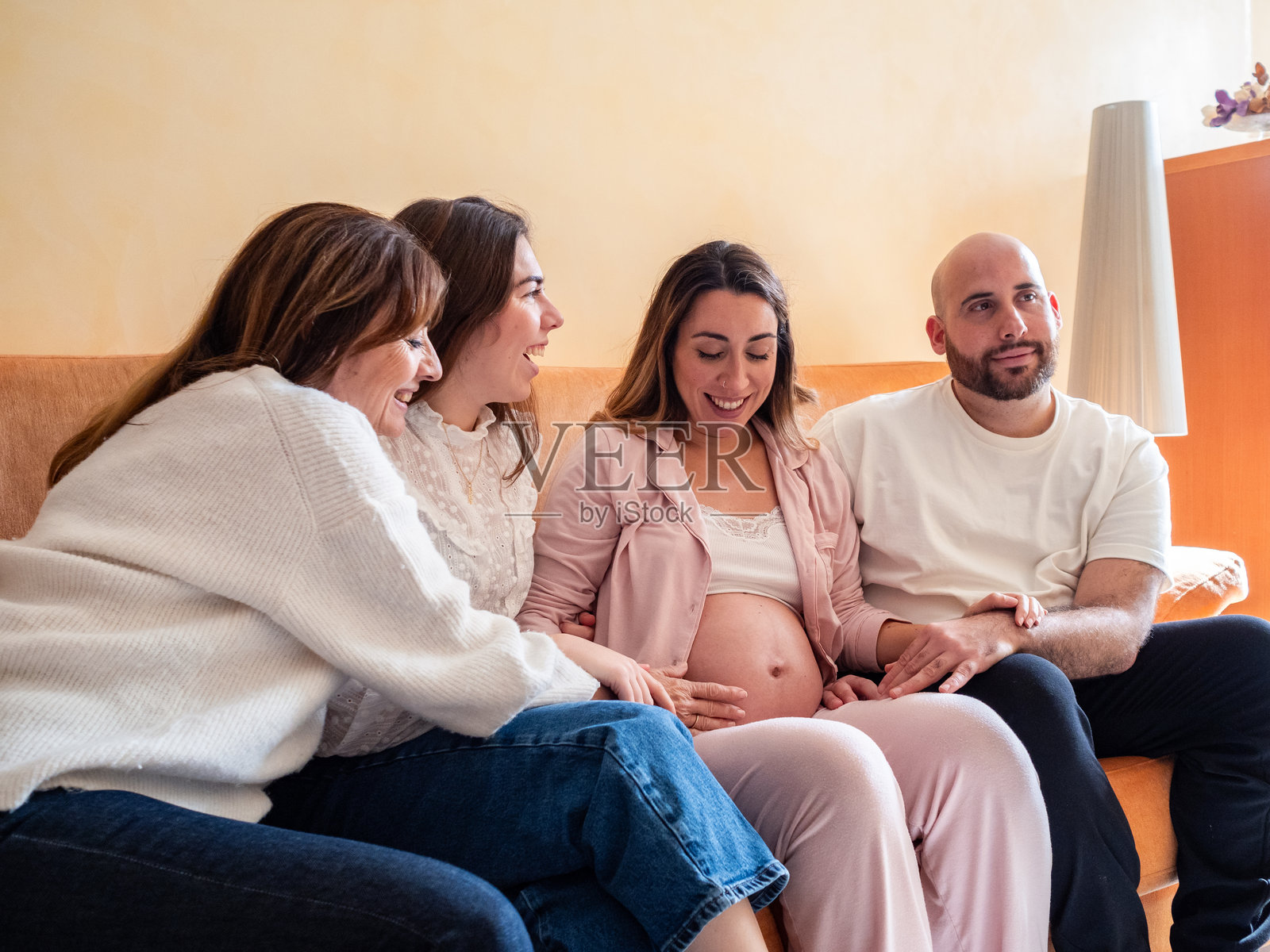 朋友和家人在温馨的客厅庆祝怀孕的喜讯照片摄影图片