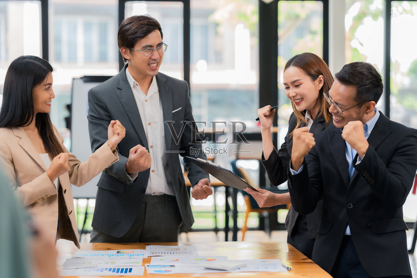 一群成功的企业在办公室举行ESG会议庆祝他们的成功，展示公司增长和营销策略的信息。同事们热烈鼓掌欢呼。照片摄影图片