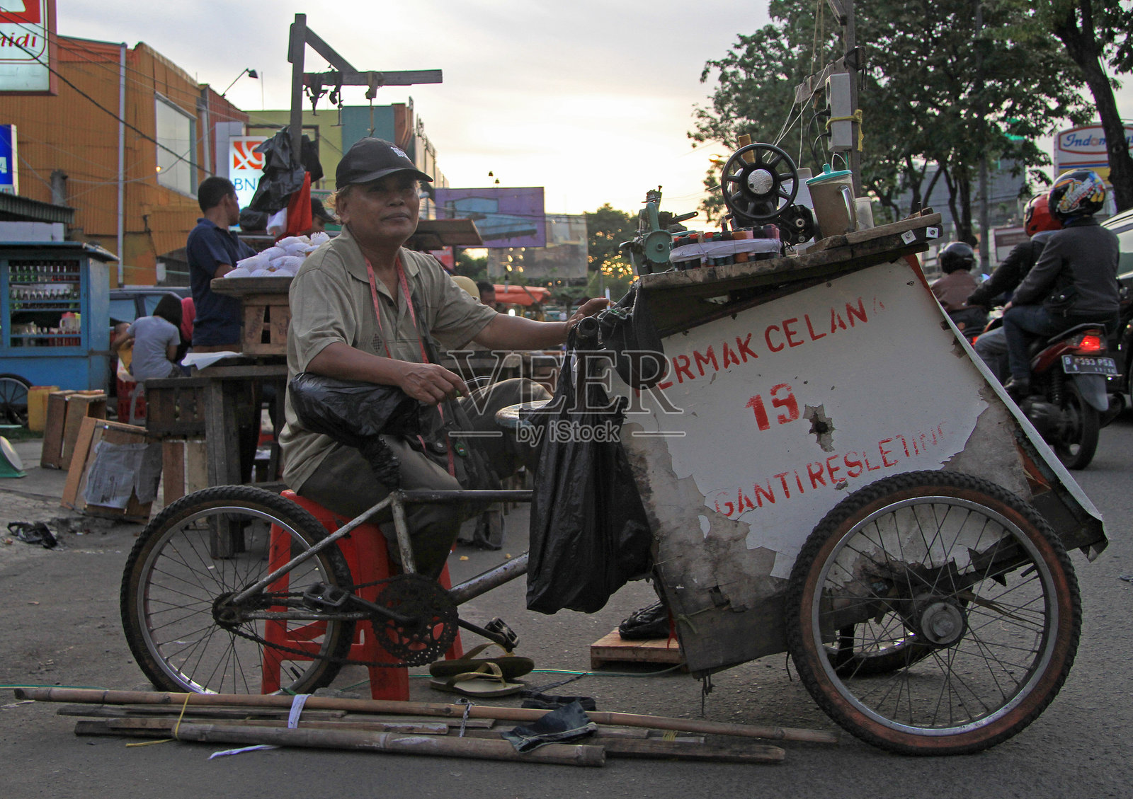 在印度尼西亚雅加达的市场上，一位身份不明的裁缝正在缝制衣物。照片摄影图片