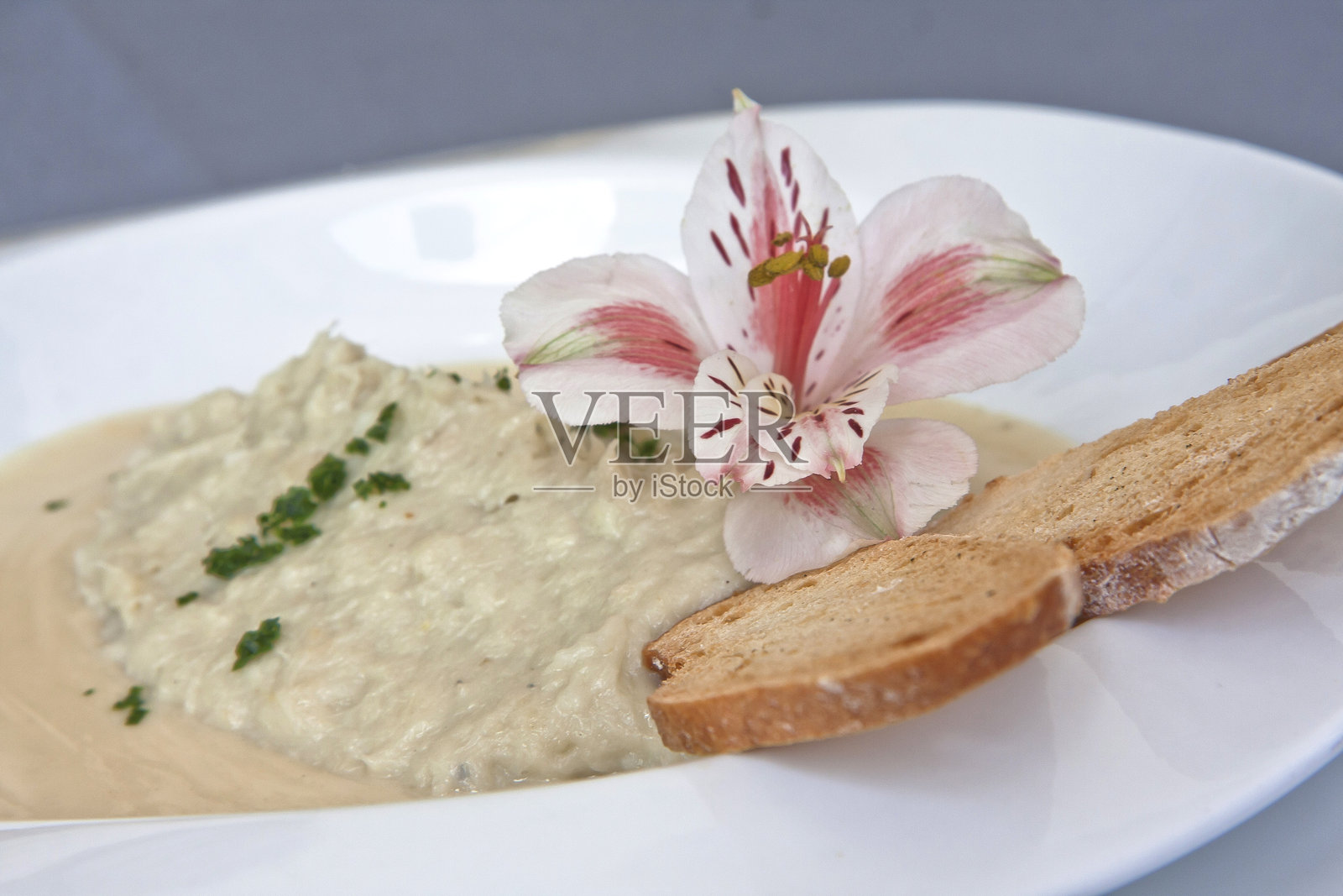 奶油蘑菇汤配上装饰有花朵的脆皮面包，素食食品照片摄影图片