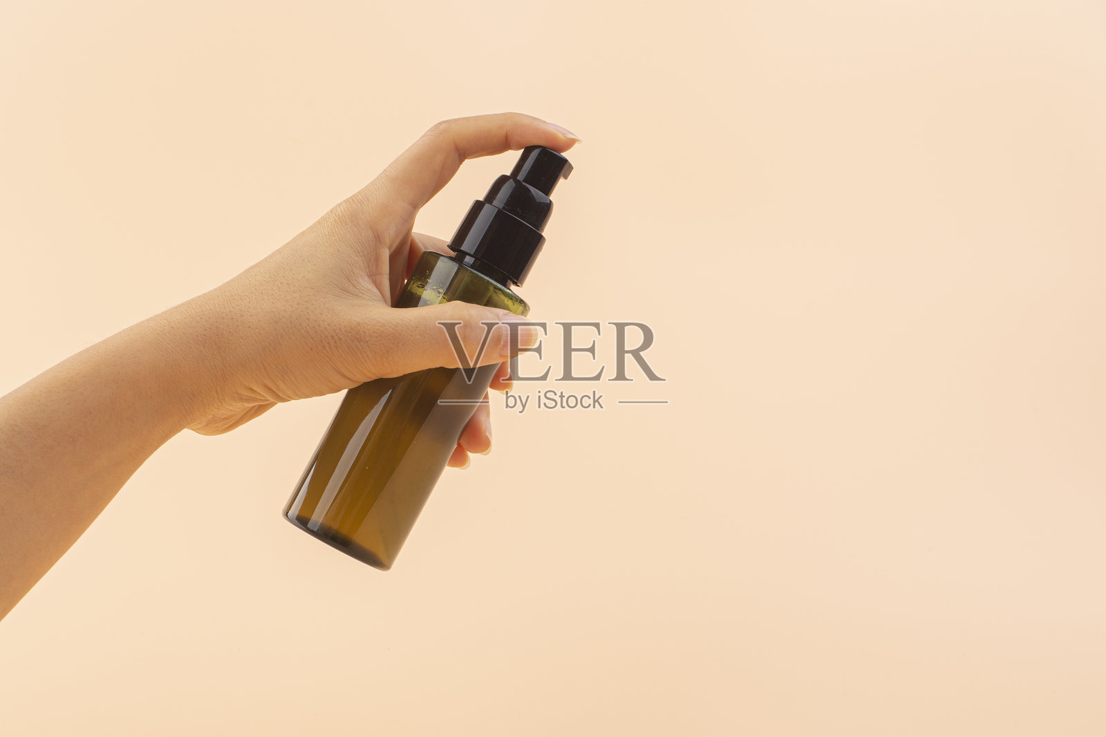 女性手握着护肤泵瓶。照片摄影图片