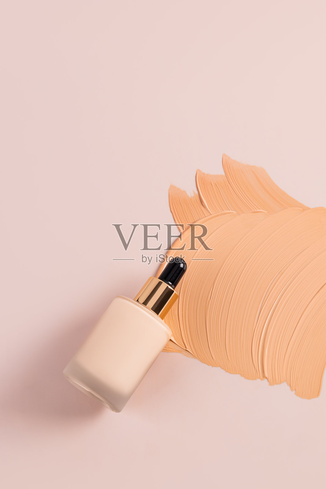 带滴管的化妆瓶，内含自然粉底粉，涂抹在米色调的液体样本纹理上。垂直俯视。留白空间。照片摄影图片