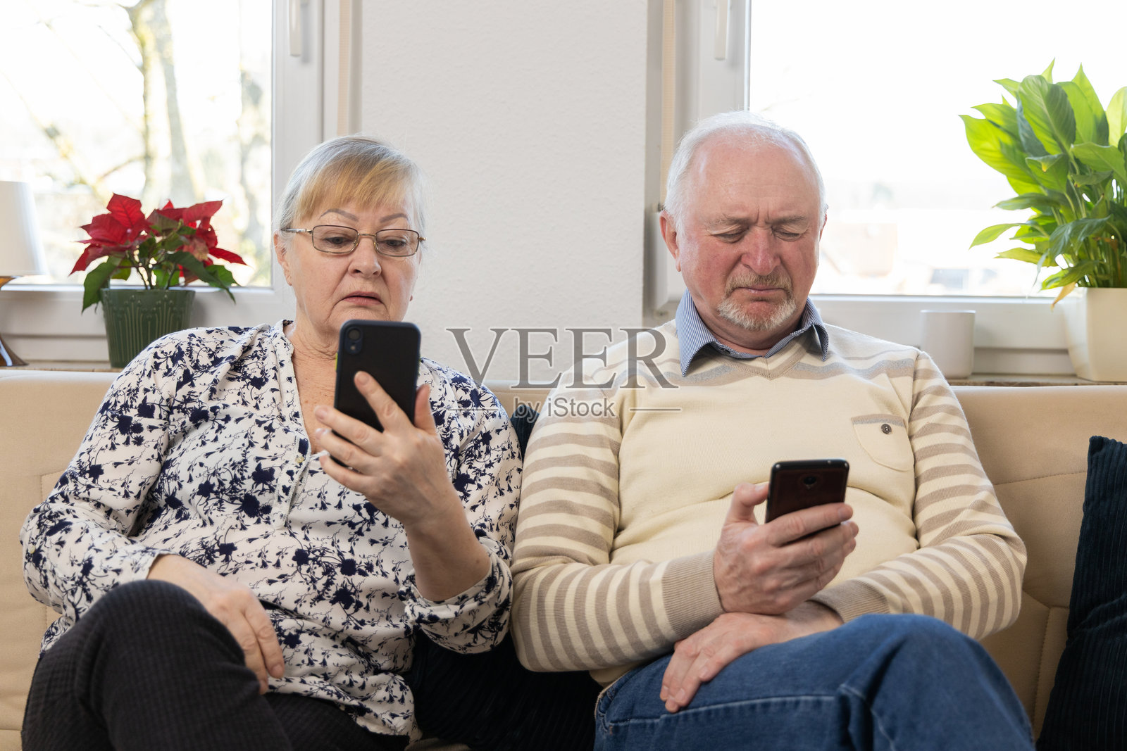 老年夫妇在使用手机。成熟的男女在网上冲浪。手机使用，手机应用，讨论在线商店购买商品，家中沙发上。照片摄影图片