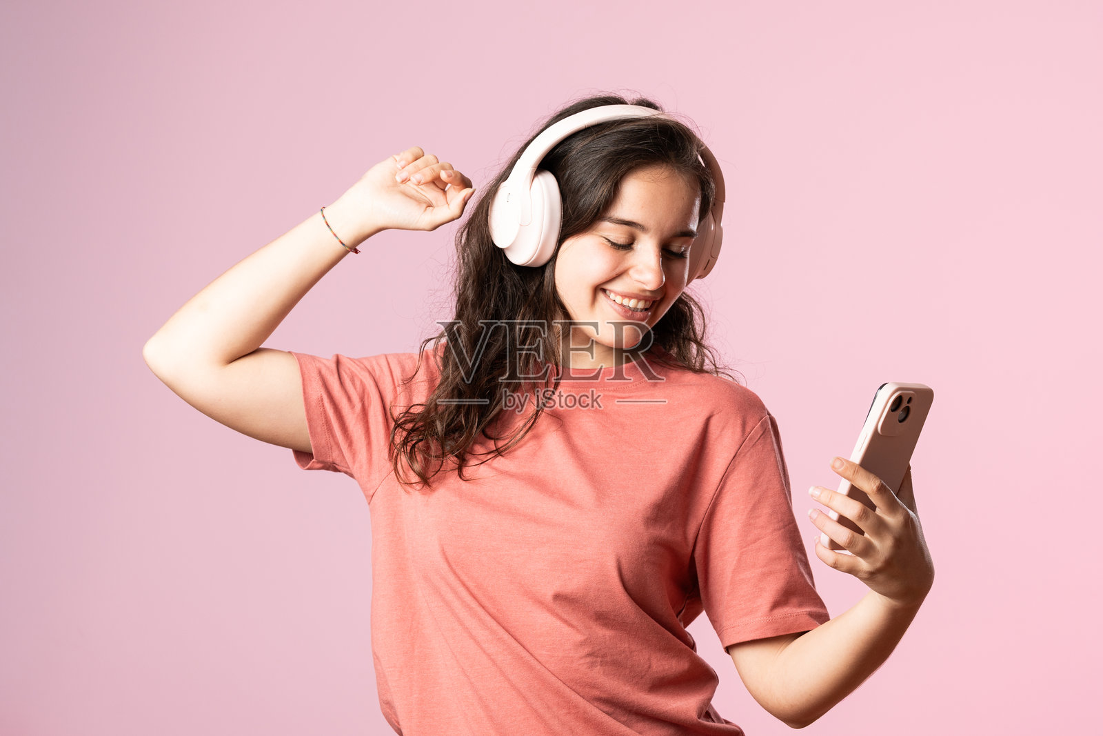 女人戴着耳机在跳舞，听着智能手机上的音乐照片摄影图片