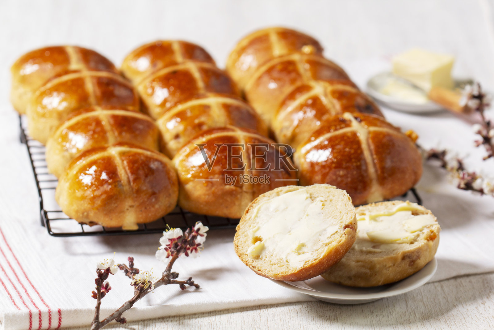 热十字面包配黄油和盛开的杏树枝。照片摄影图片