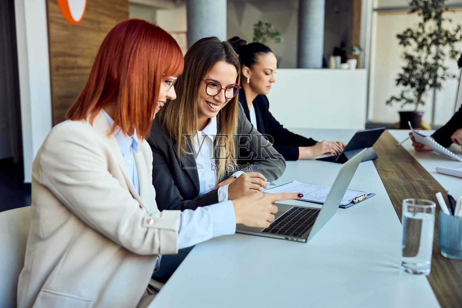 两位女商人在现代办公室环境中合作使用笔记本电脑照片摄影图片