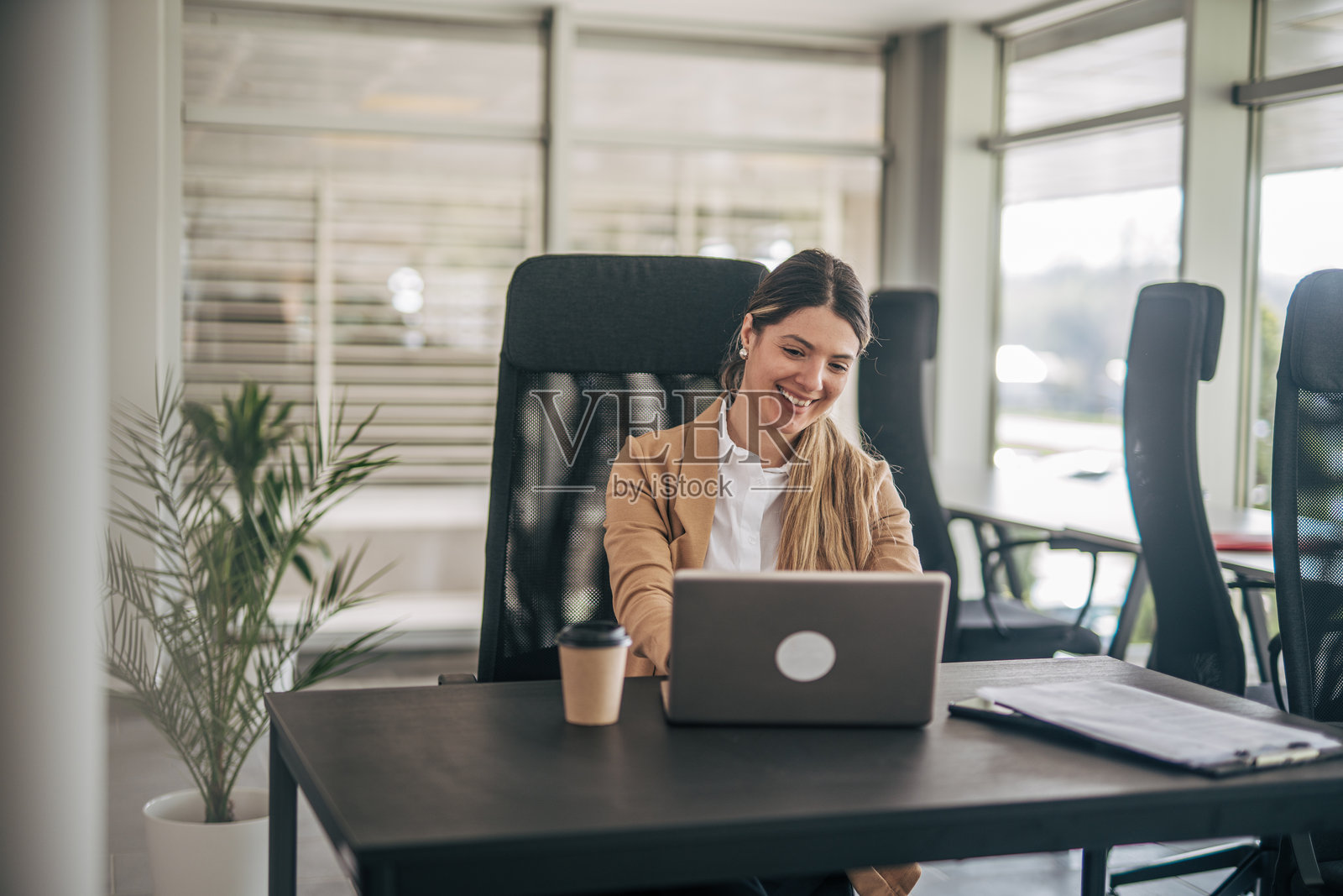 年轻女商人在现代办公室使用笔记本电脑工作照片摄影图片