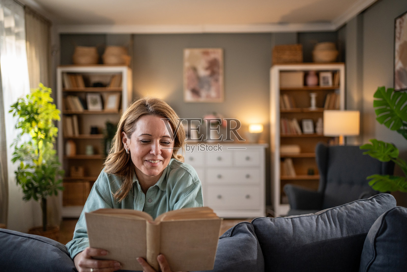 微笑的女性在家中的客厅里阅读一本书照片摄影图片