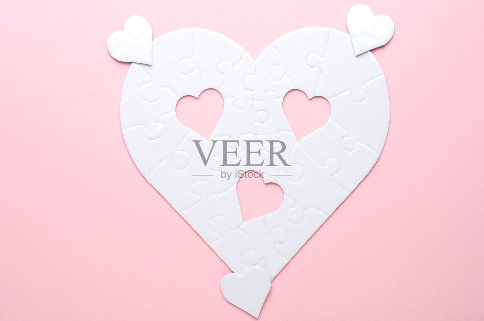 灰色背景上的白色心形拼图，缺少几块拼图并放置在旁边。象征着爱、连接或不完整，适合与关系和情感相关的主题。照片摄影图片