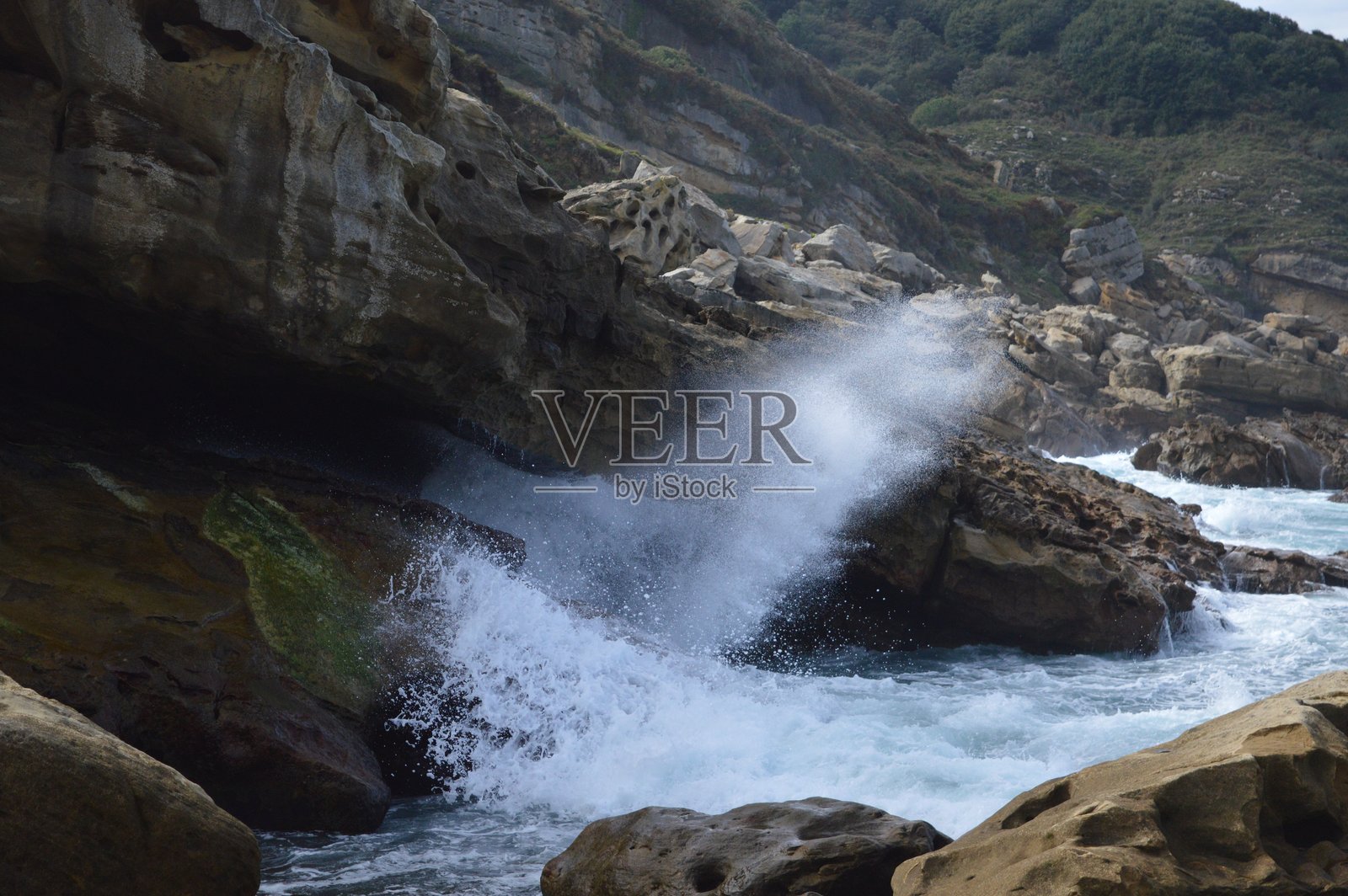 海浪拍打岩石，溅起水花照片摄影图片