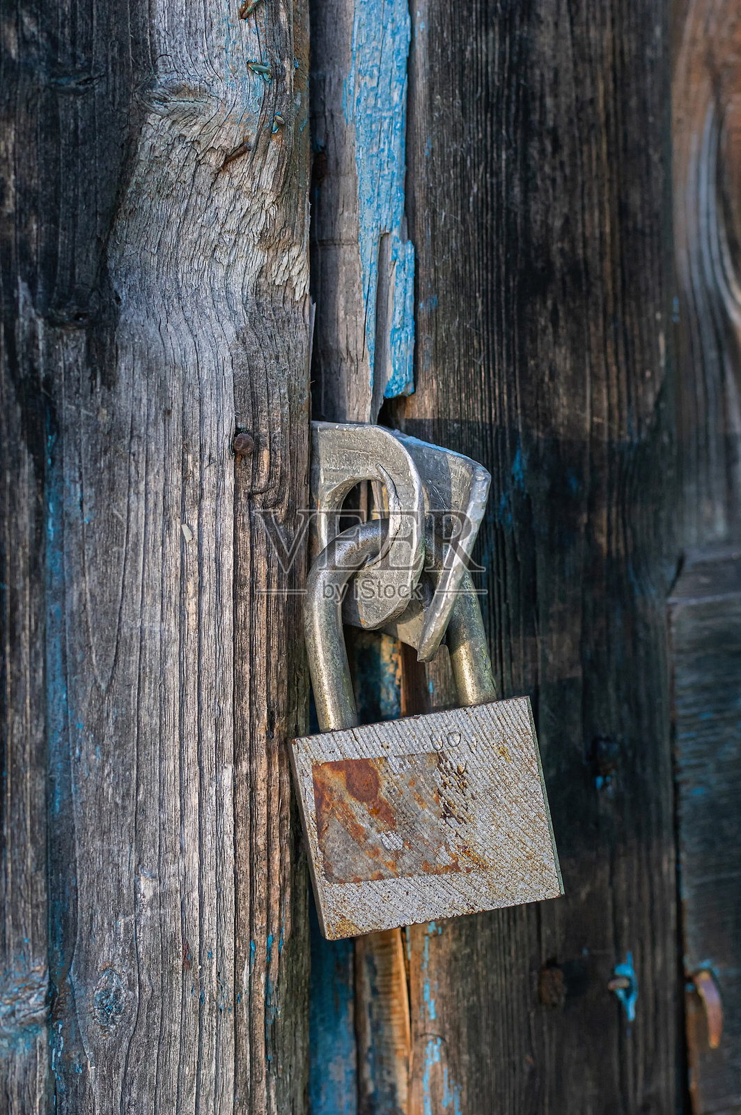 生锈的挂锁锁住风化的木门。竖向裁剪。照片摄影图片