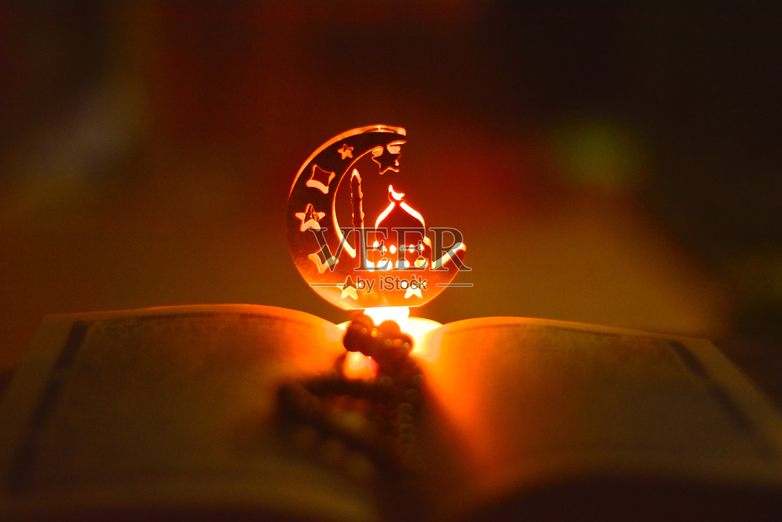 夜间微光下，古兰经上方的清真寺形状的拉马丹装饰灯饰。照片摄影图片