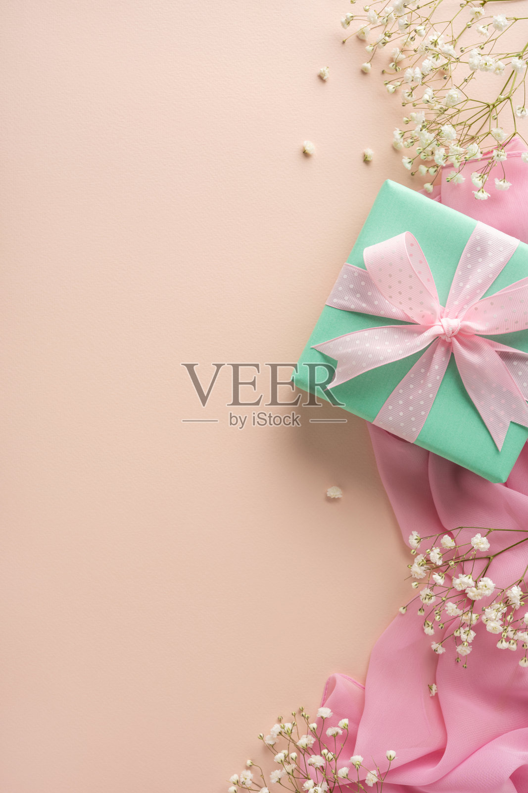精致的垂直粉彩构图，包含礼品盒、粉色丝带、轻薄面料和象征庆祝、问候或特殊场合的满天星花，展现柔和与女性气息。照片摄影图片