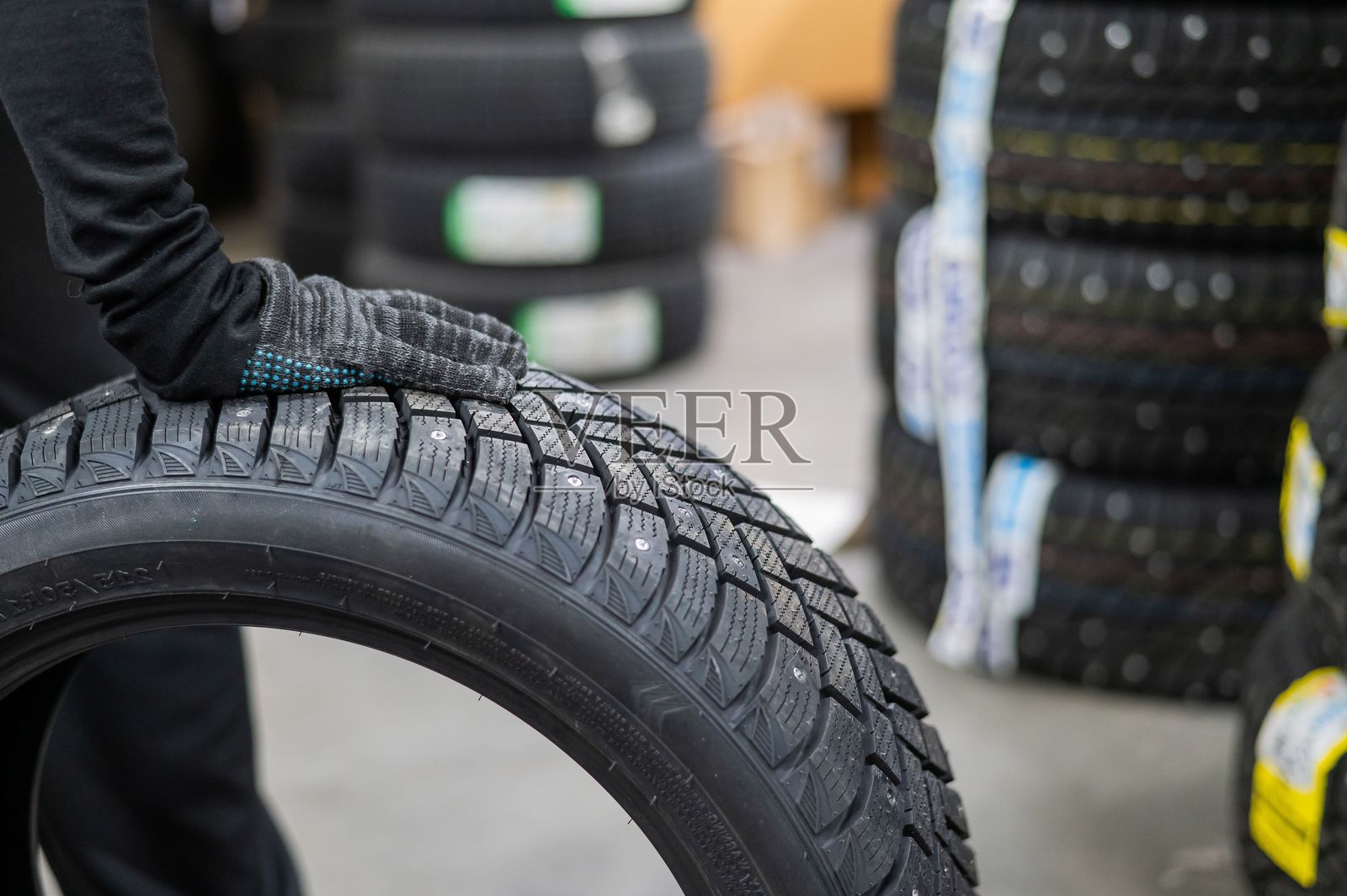 机械师在车库里存放新的带钉轮胎。照片摄影图片