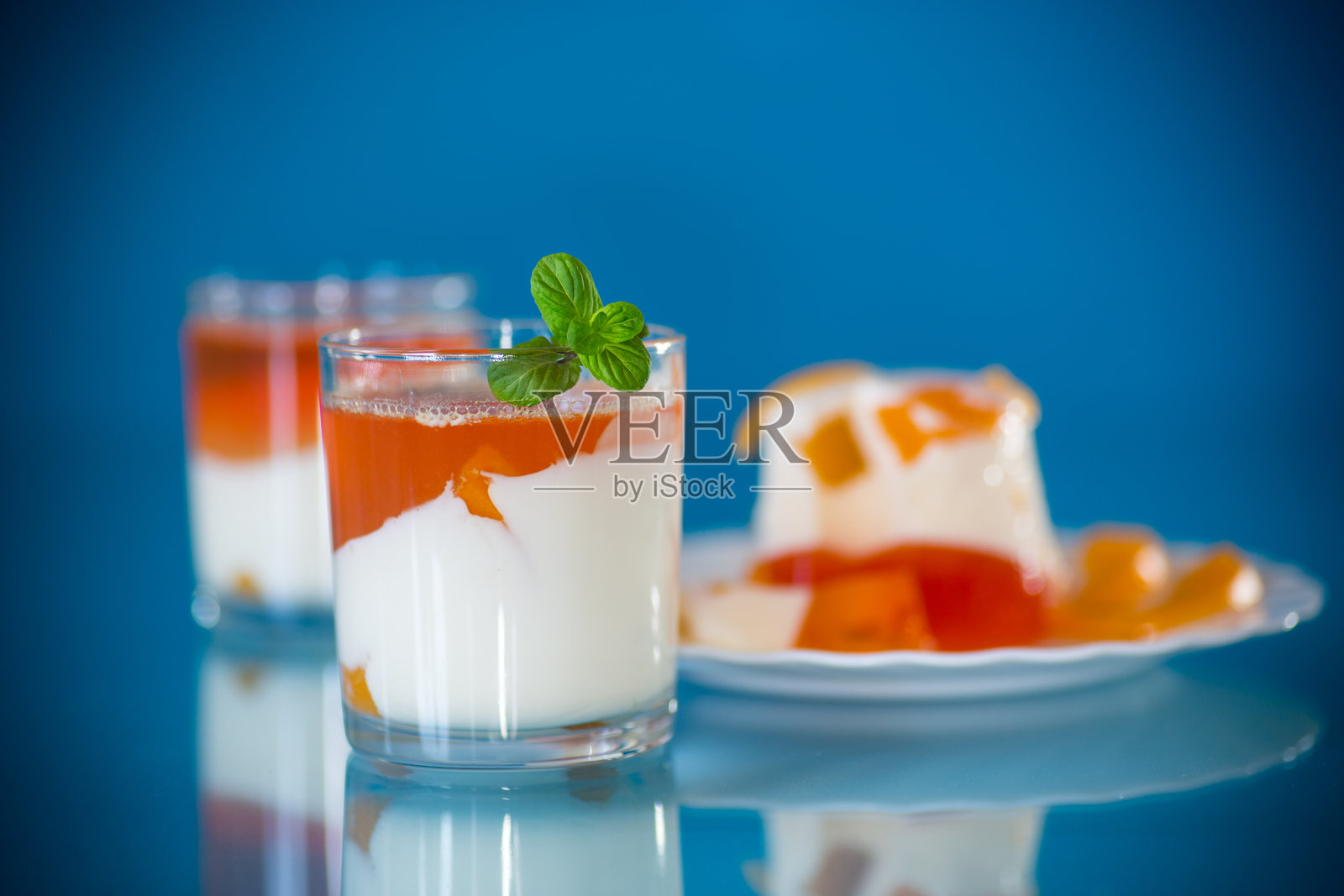 分装在玻璃杯中的果冻甜点，配有酸奶奶油和水果照片摄影图片