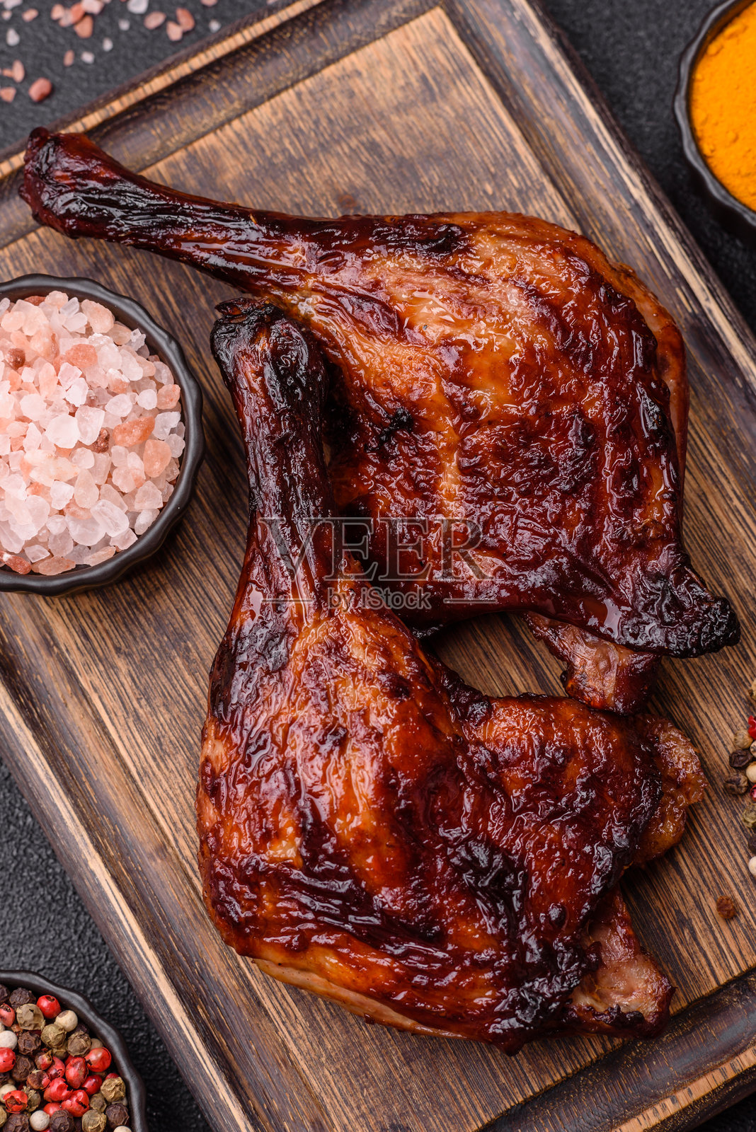在深色混凝土背景上烤制的鸭肉、鸡腿或鸡大腿照片摄影图片
