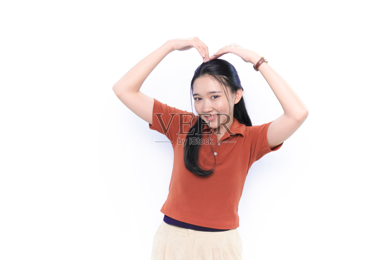 穿着橙色衬衫的印尼亚洲模特微笑并做出爱心手势照片摄影图片