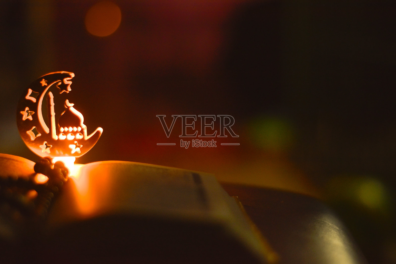 夜间微光下，古兰经上方的清真寺形状的拉马丹装饰灯饰。照片摄影图片