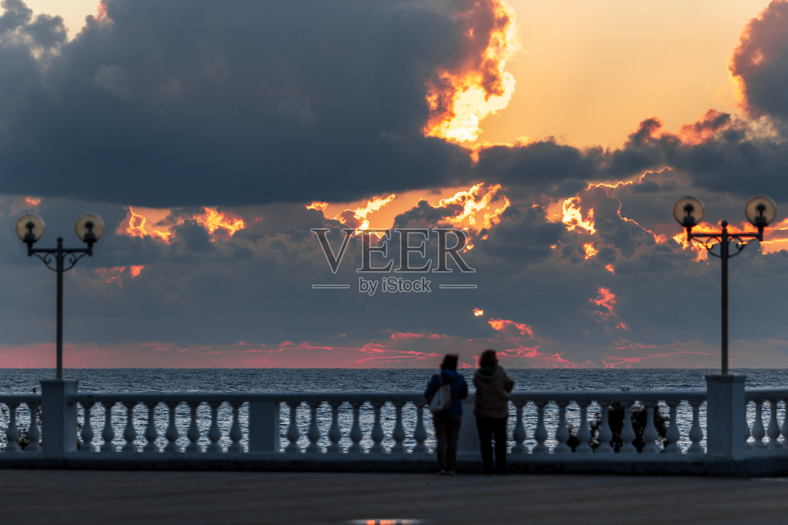 格伦吉克度假村。两个人站在码头上眺望海洋。照片摄影图片