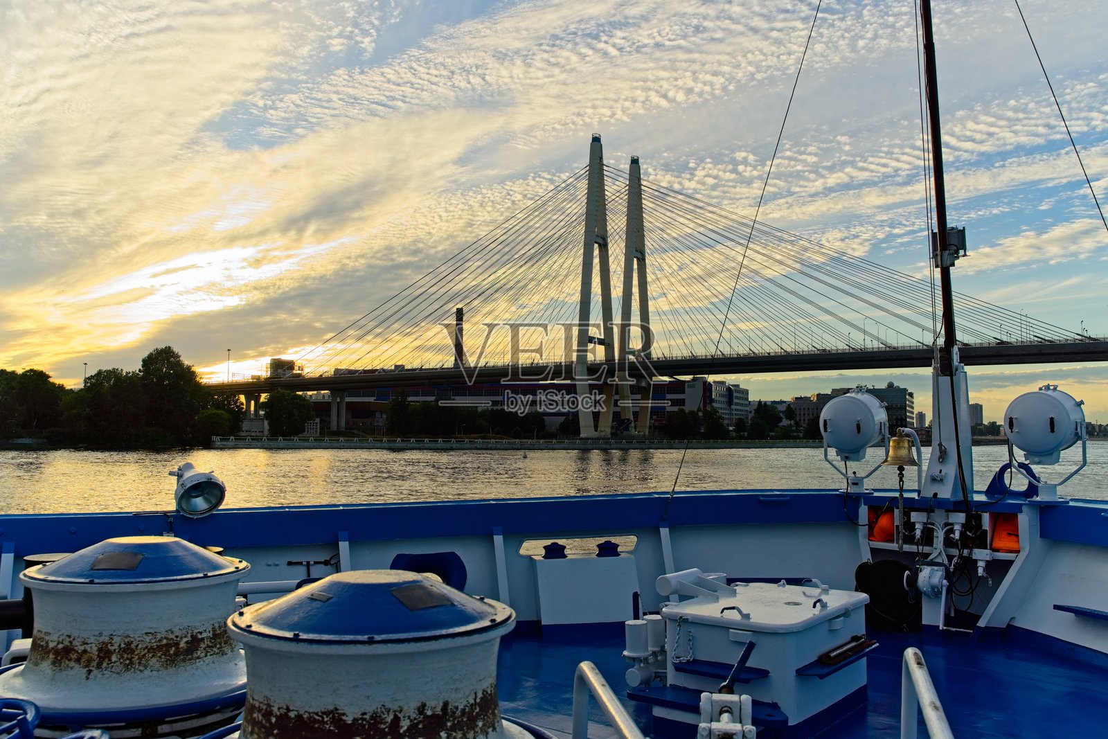 从船上看日落时的斜拉桥景观。照片摄影图片