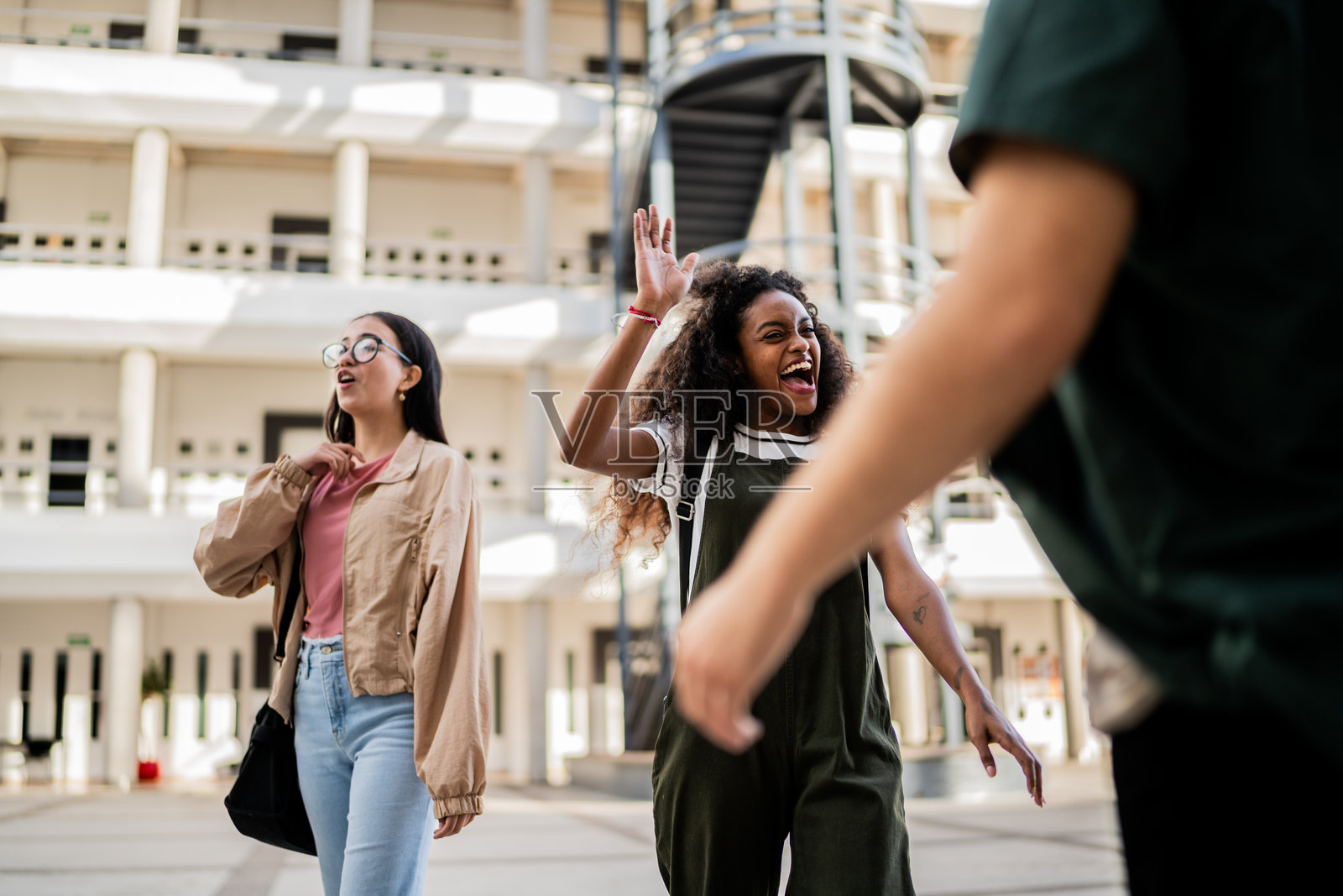 年轻女学生在大学里向朋友打招呼照片摄影图片