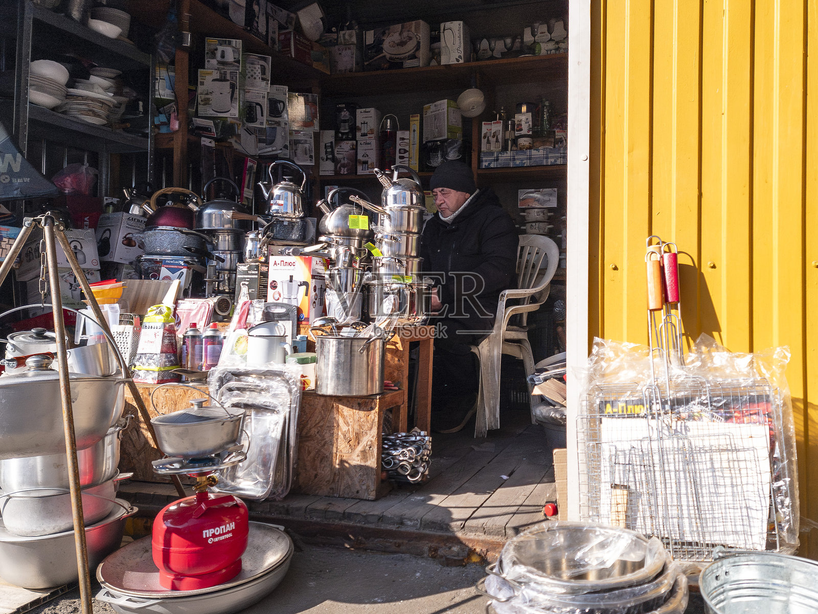 在繁忙的基辅市场中心,一位摊贩向路过的当地人和游客展示各种厨房用品和器具。照片摄影图片