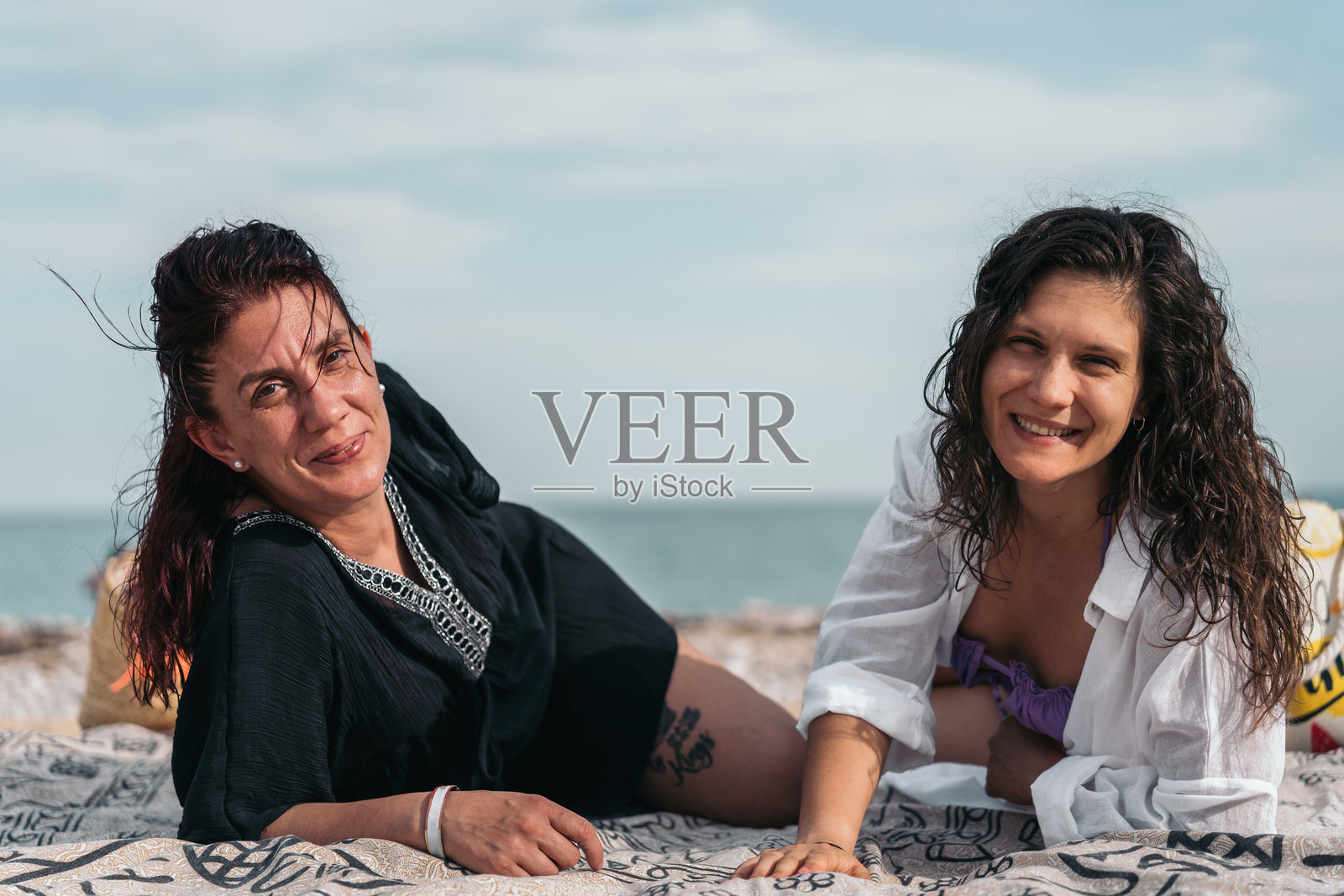 两位女性在海滩毛巾上微笑放松照片摄影图片