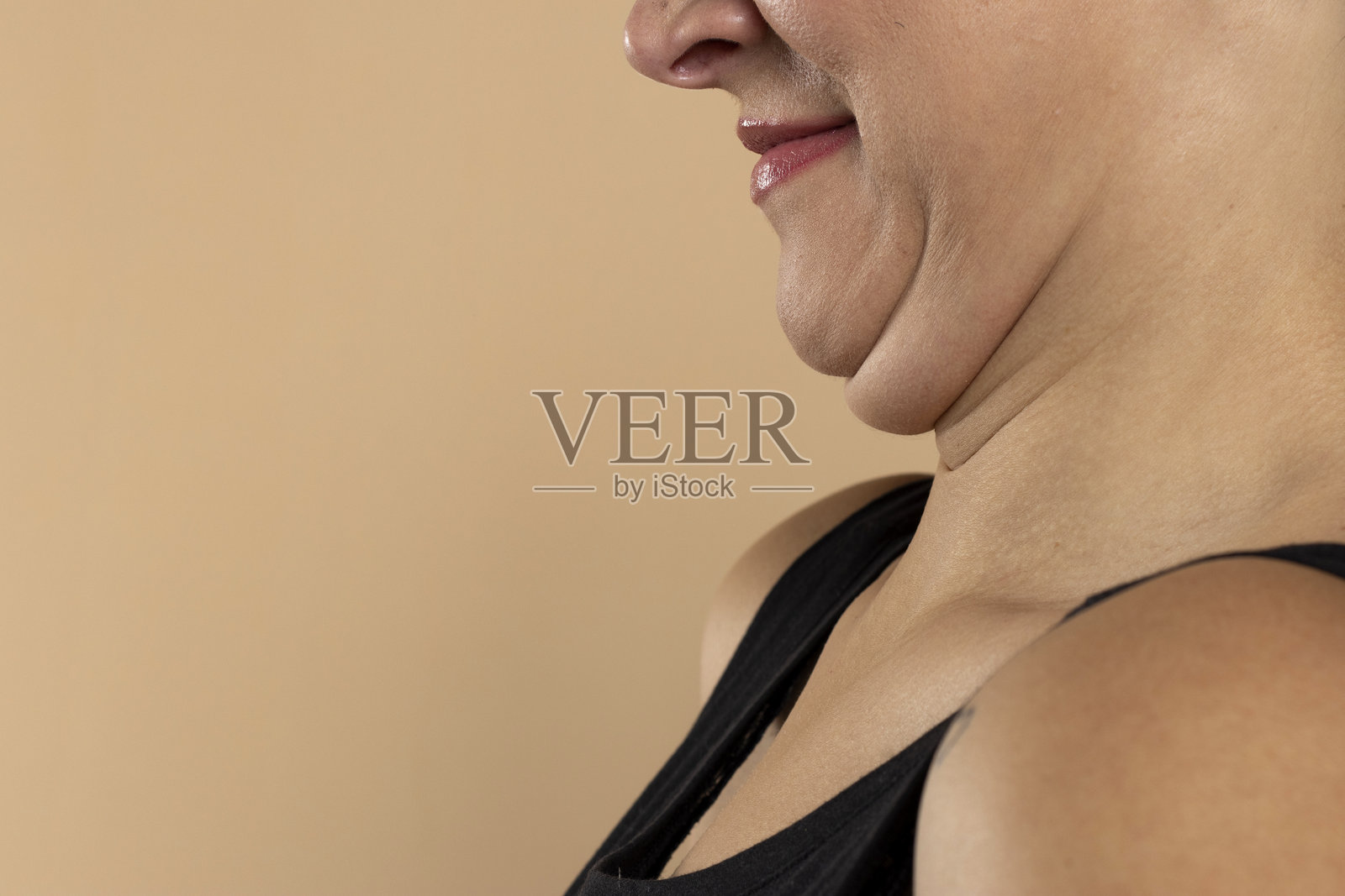 年轻女性在米色背景下的特写，双下巴。留有文字空间。照片摄影图片