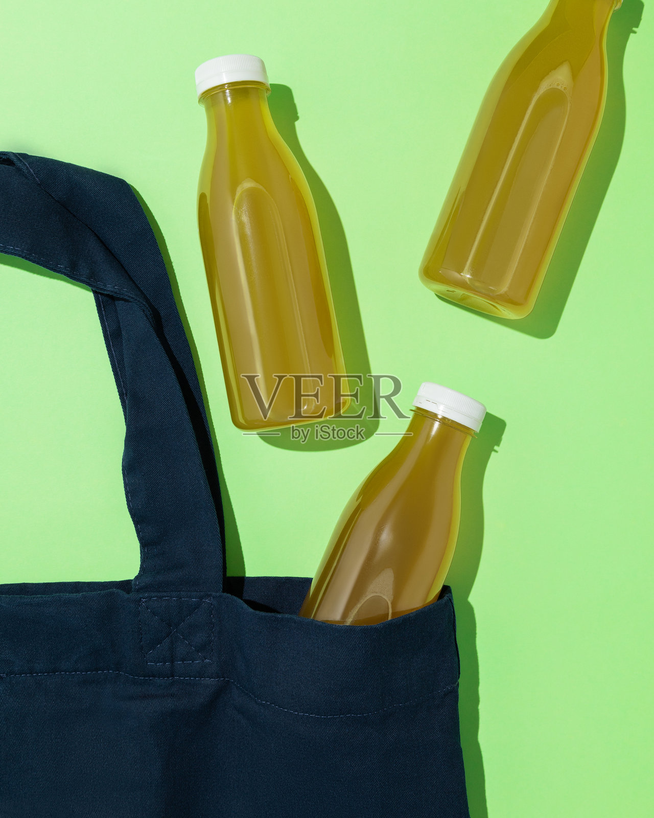 三瓶西兰花汁从一个袋子里出来，背景是绿色，象征着健康和积极的生活方式。照片摄影图片