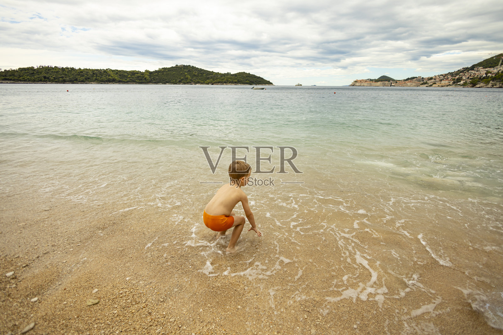 海滩上的幼儿，望着海岸线的地平线并玩耍照片摄影图片