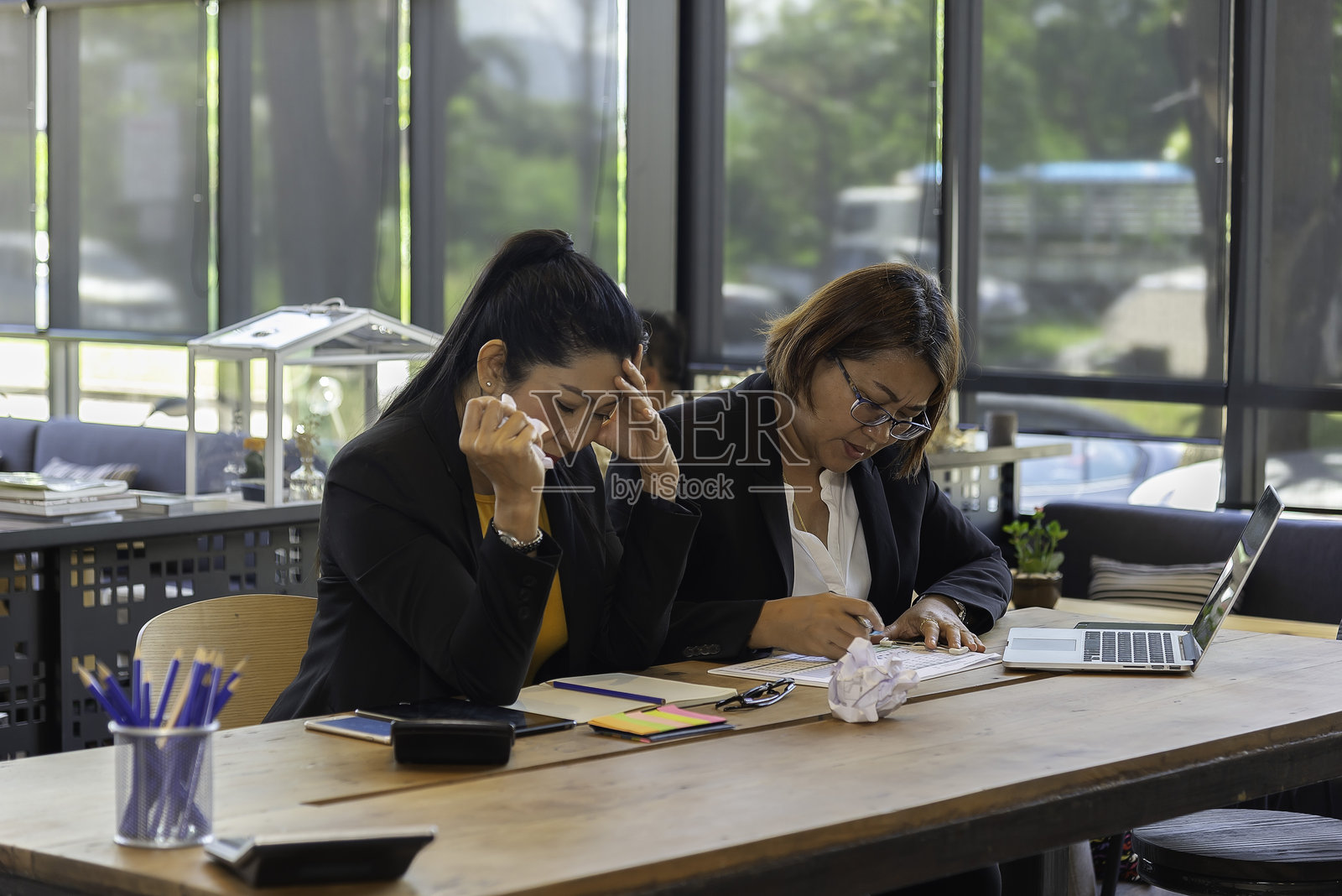 两位女商人在桌子旁讨论项目细节，多元化的女性同事在办公室会面，分享意见，共同完成任务。照片摄影图片
