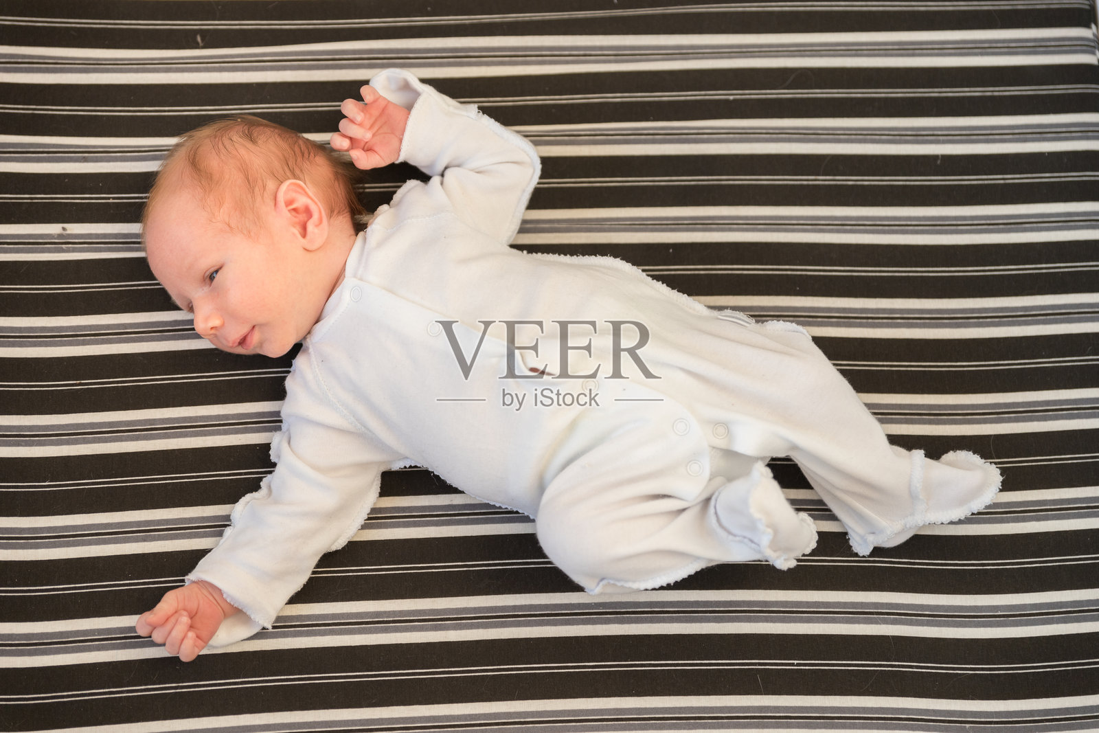 一个穿着白色服装的白人新生儿仰卧着。照片摄影图片