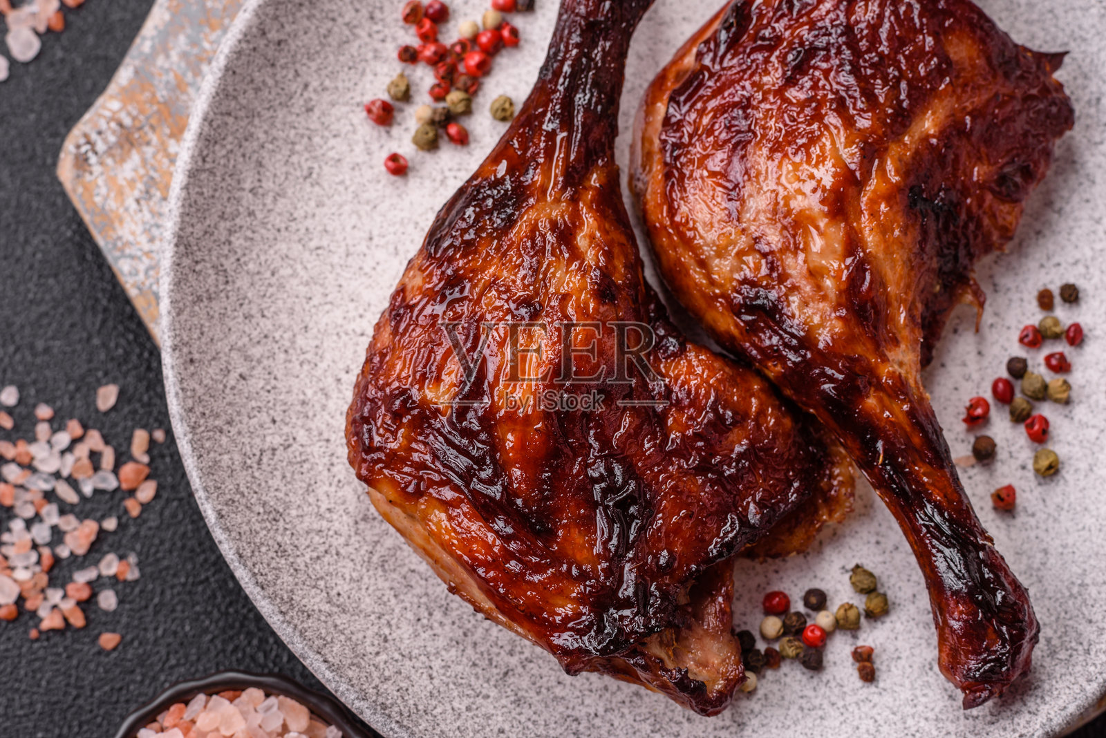 在深色混凝土背景上烤制的鸭肉、鸡腿或鸡大腿照片摄影图片