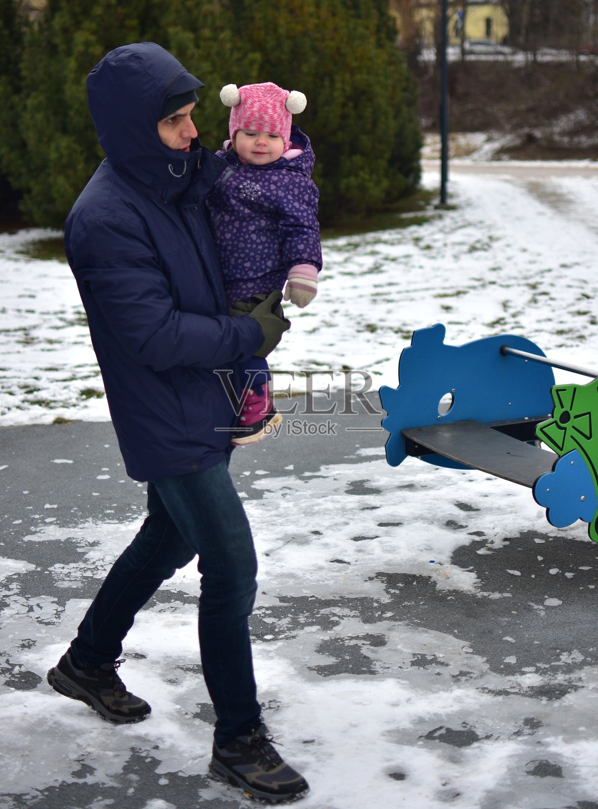 父亲在寒冷的冬季城市公园里抱着他的女儿。爸爸和女儿一起度过美好时光。爸爸将小女孩抱在怀里。照片摄影图片