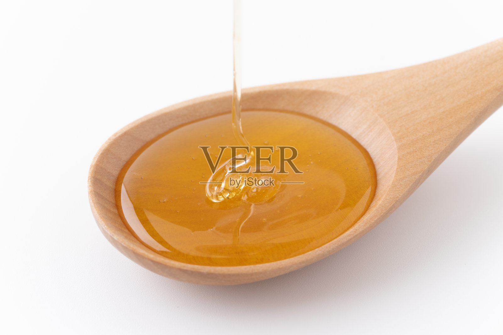 蜂蜜滴在木勺上，背景为白色照片摄影图片