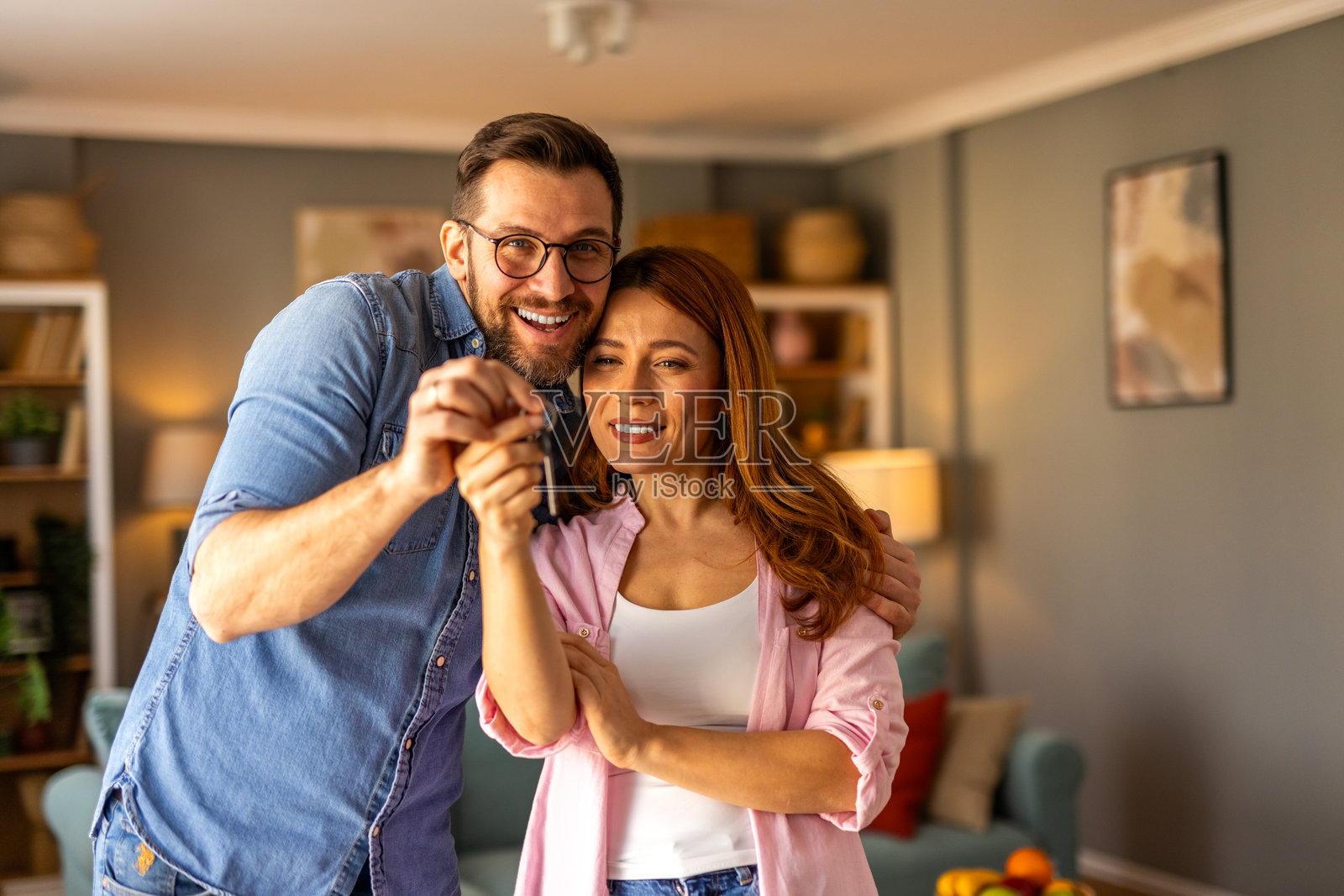 一对夫妇站在一起，开心地展示他们新家的钥匙。这个画面捕捉了兴奋、成就和新的开始，他们在欢庆拥有自己的家。照片摄影图片