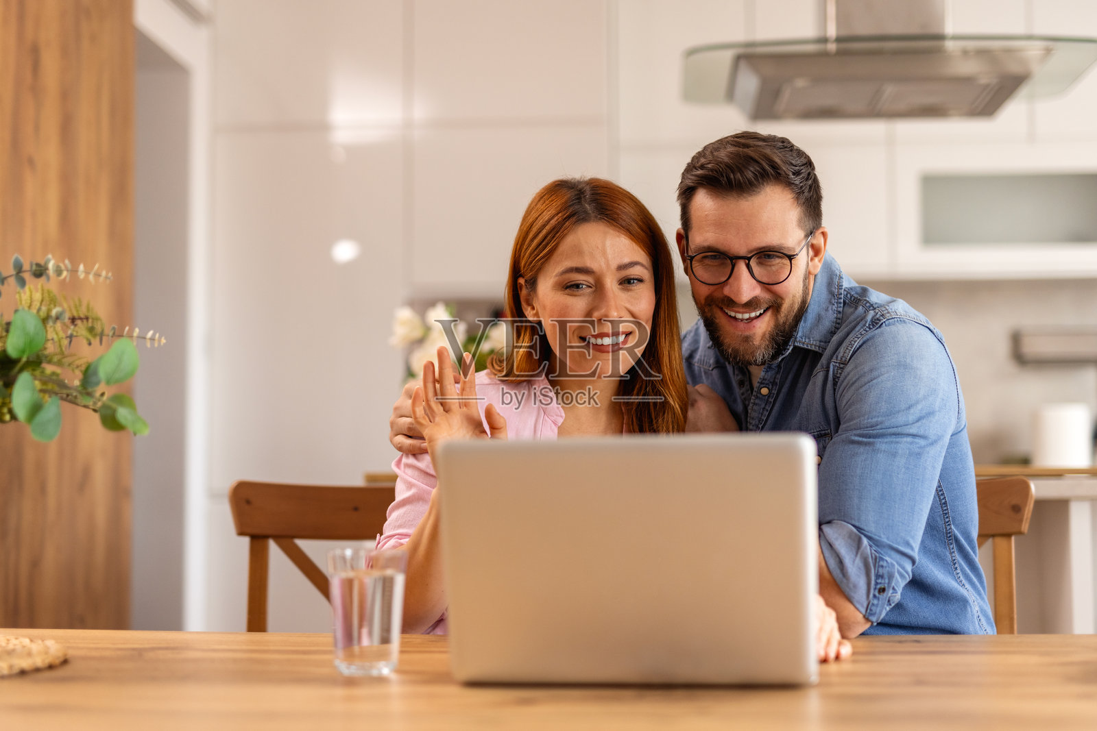 一对情侣坐在桌子旁，一起使用笔记本电脑。这个场景展现了团队合作、沟通或共享活动，反映了现代科技和协作。照片摄影图片
