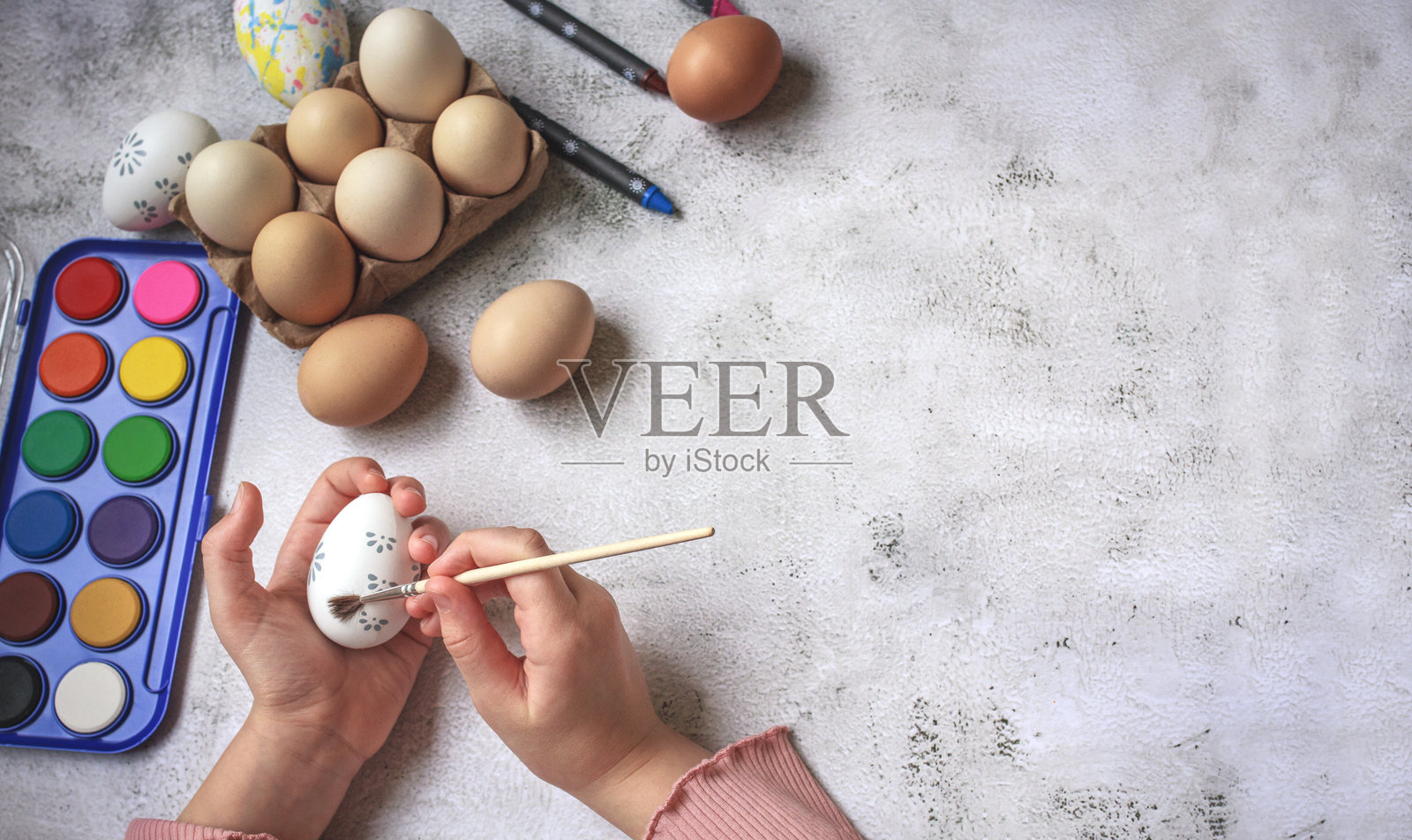 小女孩在混凝土背景上为复活节绘制彩蛋，留有空白空间。照片摄影图片